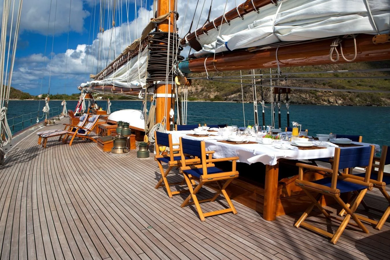 a deck with tables and chairs on it next to a body of water aboard ELEONORA E Yacht for Sale