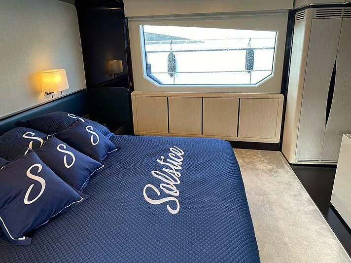 a bed with blue sheets and pillows aboard SOLSTICE Yacht for Sale