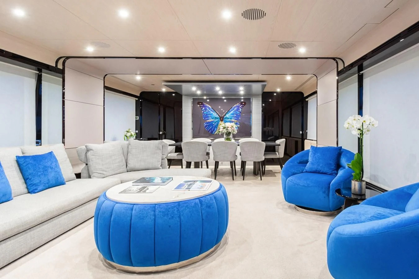 a large living room with a blue couch and a large blue table aboard SOLSTICE Yacht for Sale