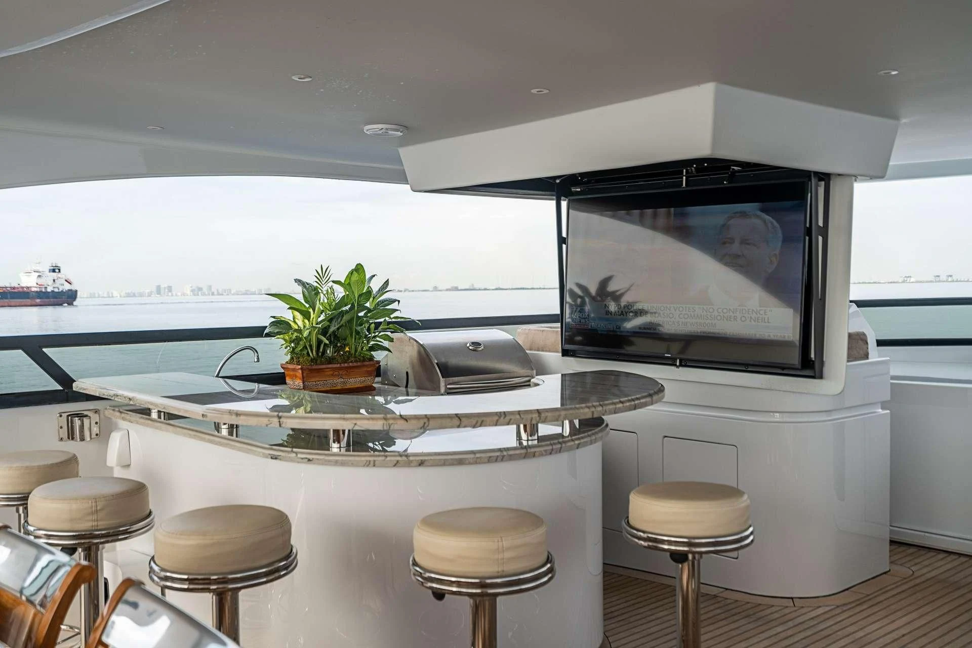 a kitchen with a tv and stools aboard CAMILLE Yacht for Sale