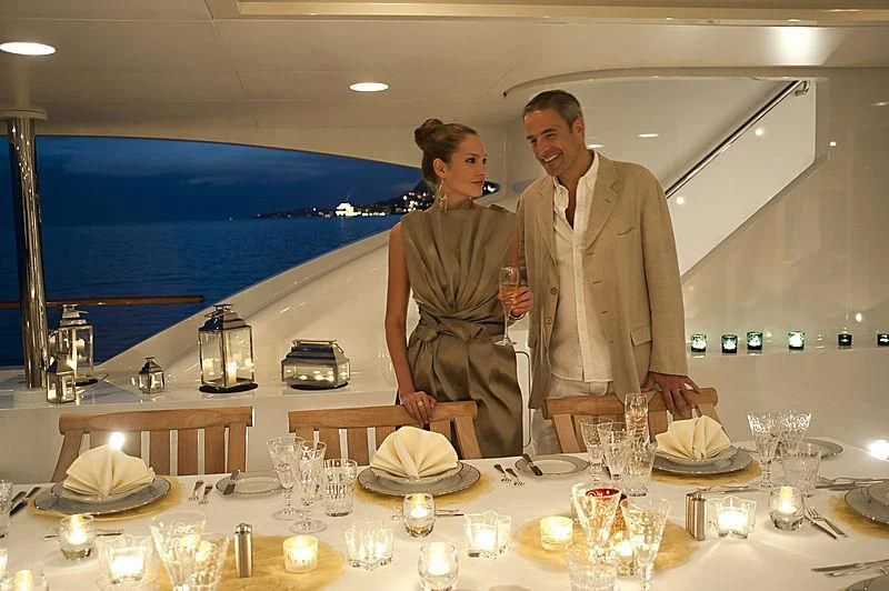 a group of people standing around a table with wine glasses aboard LA BLANCA Yacht for Sale