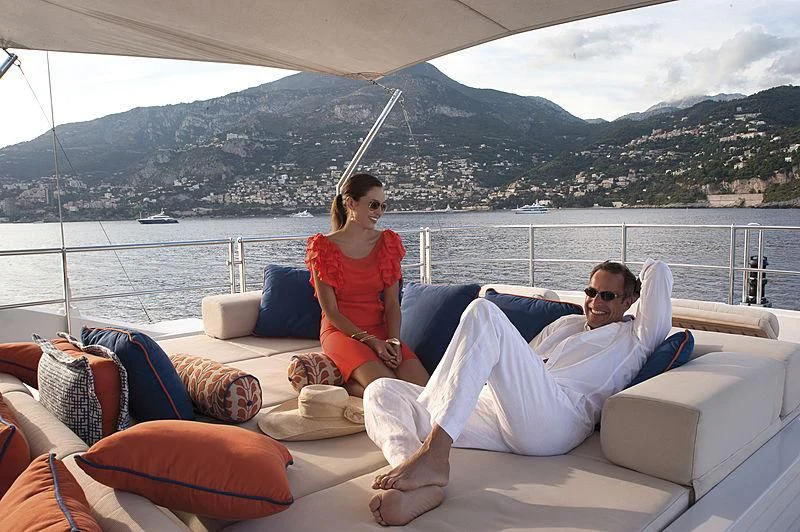 a man and woman sitting on a boat with a view of mountains aboard LA BLANCA Yacht for Sale