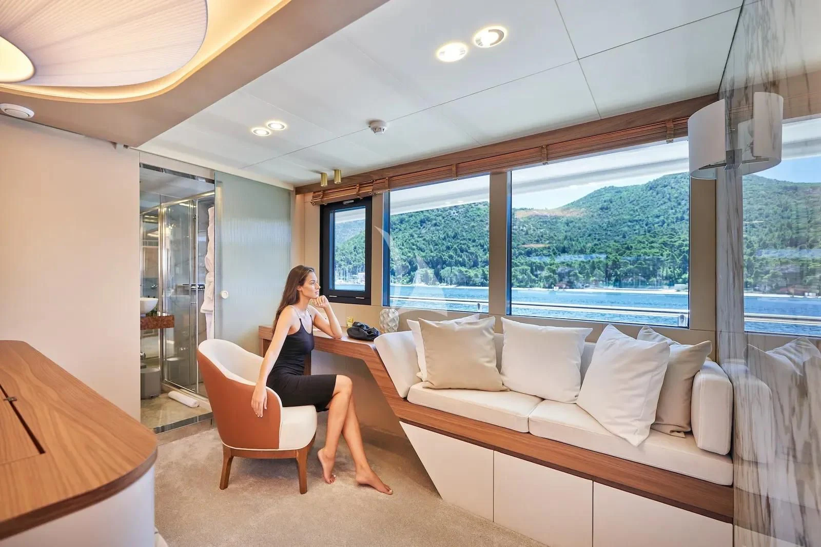 a person sitting on a couch in a room with a large window aboard AETERNA Yacht for Sale
