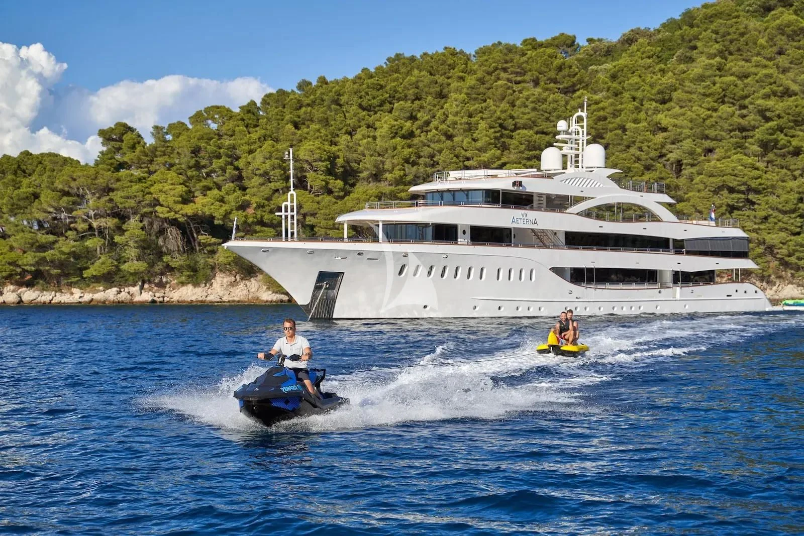 people on jet skis in front of a large boat aboard AETERNA Yacht for Sale