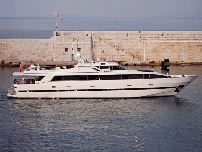 a white boat in front of a wall with a flag on it aboard AVELLA Yacht for Sale