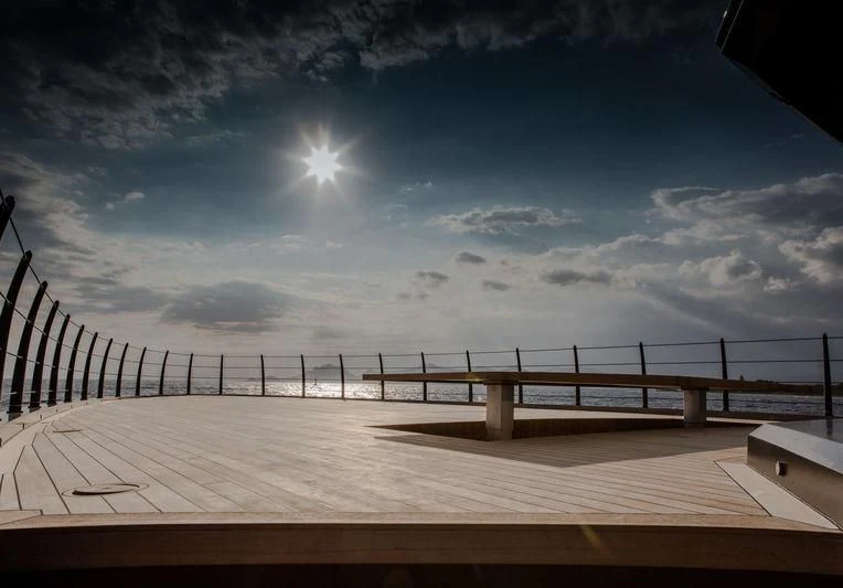 a wooden dock with a railing and the sun in the background aboard ATLANTE Yacht for Sale