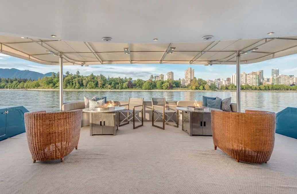 a group of chairs and tables under a covered area with a city in the background aboard ASCENTE Yacht for Charter