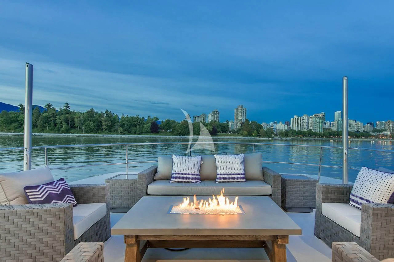 a table with a fire pit and a view of a city aboard ASCENTE Yacht for Charter