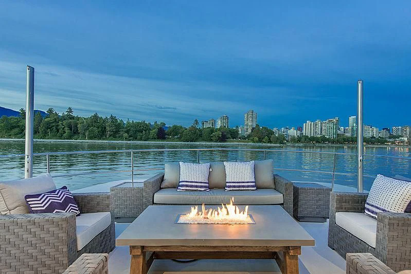 a table with chairs and a fire pit on a deck overlooking a city aboard ASCENTE Yacht for Charter