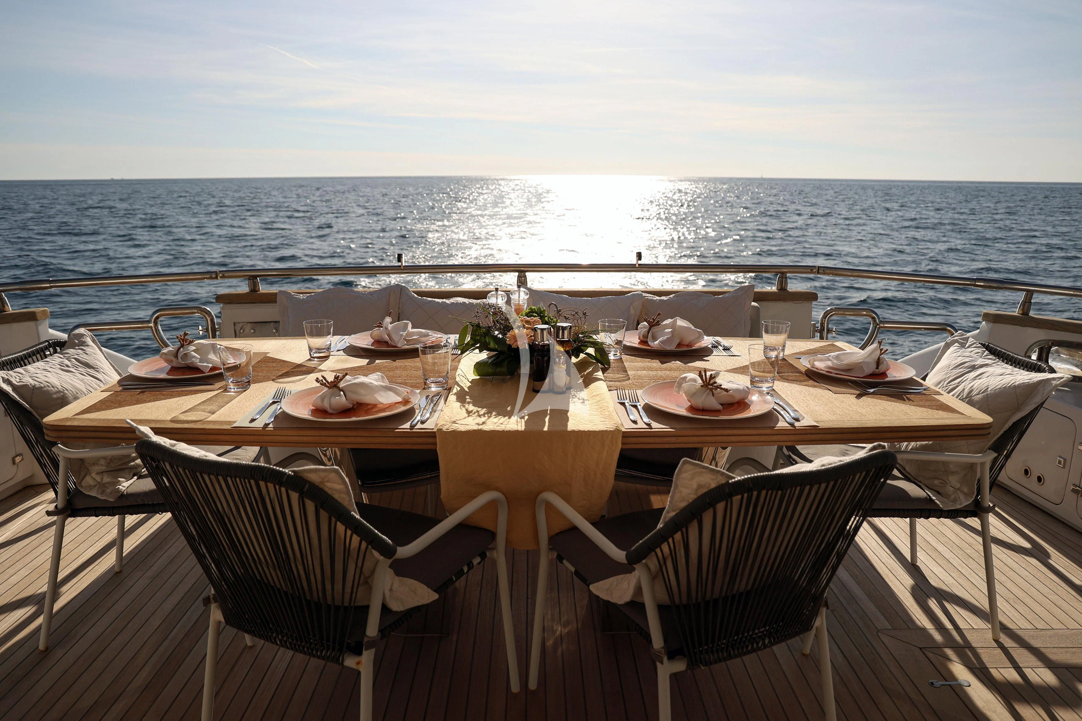 a table set for a meal on a deck overlooking a large body of water aboard WILLFUL Yacht for Sale