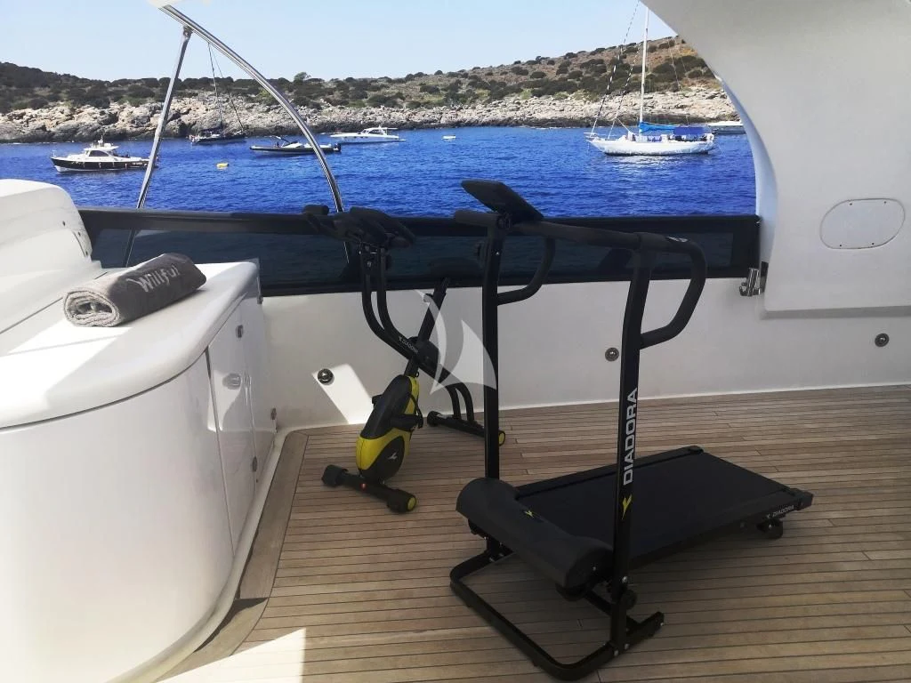 a black and yellow chair on a wood deck next to a boat aboard WILLFUL Yacht for Sale