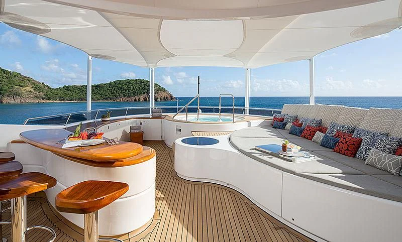 a large white lounge chair next to a large white table with a large white table and chairs on aboard REVERIE Yacht for Sale