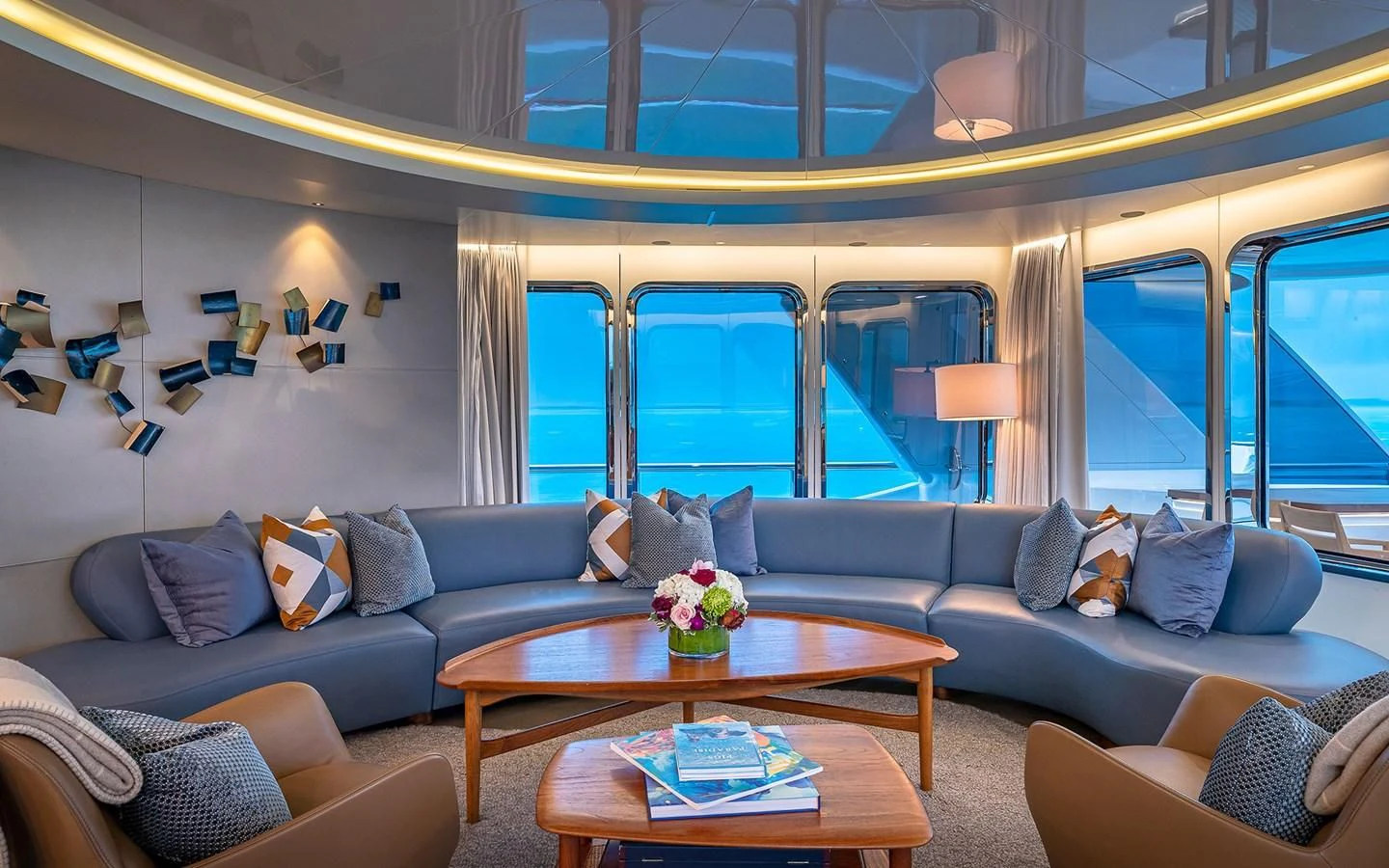 a living room with a blue couch and a large window aboard REVERIE Yacht for Sale