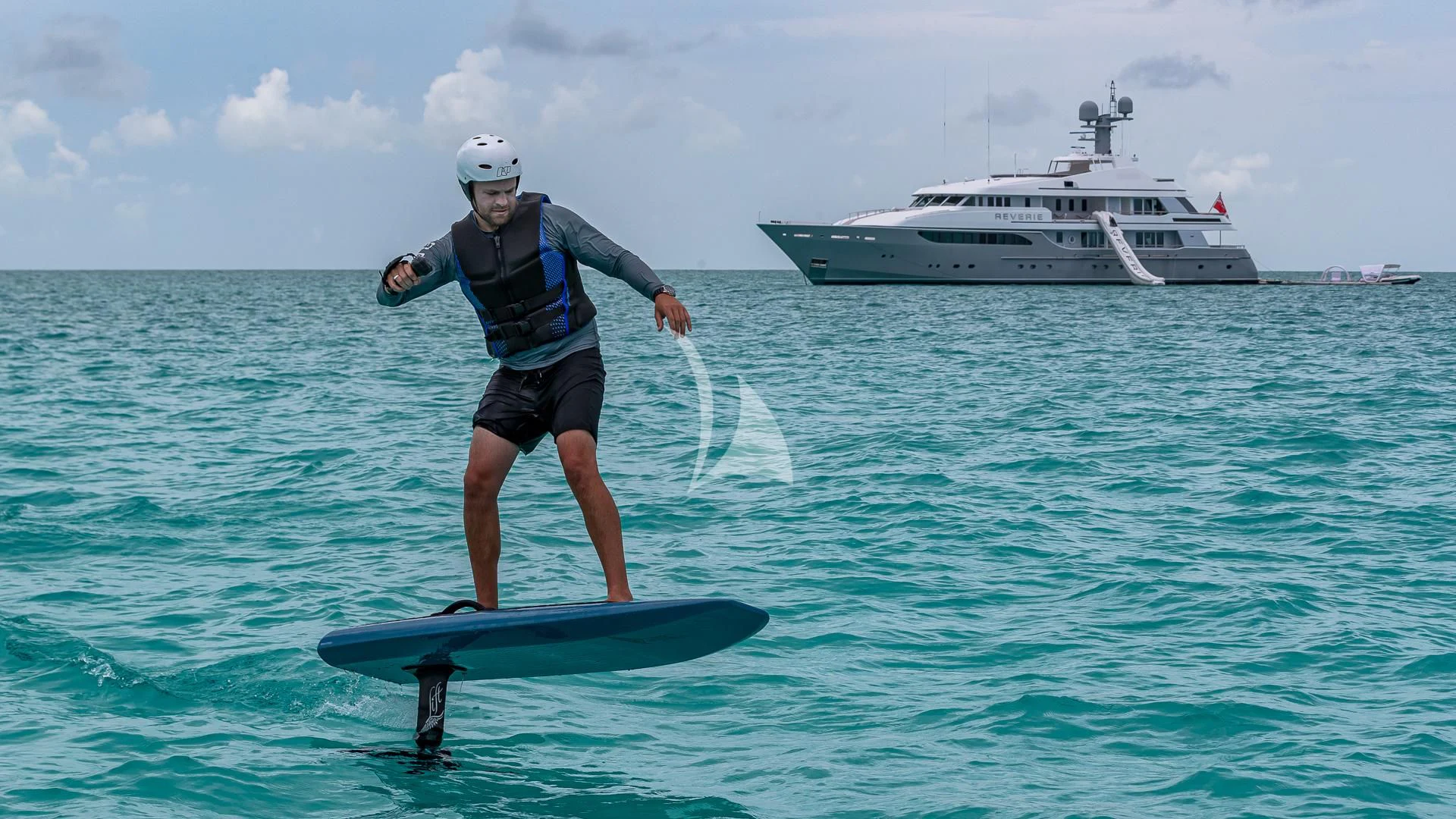 a man on a surfboard in the water with a boat in the background aboard REVERIE Yacht for Sale