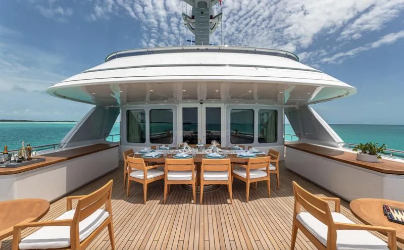 a deck with chairs and tables on it by the water aboard REVERIE Yacht for Sale