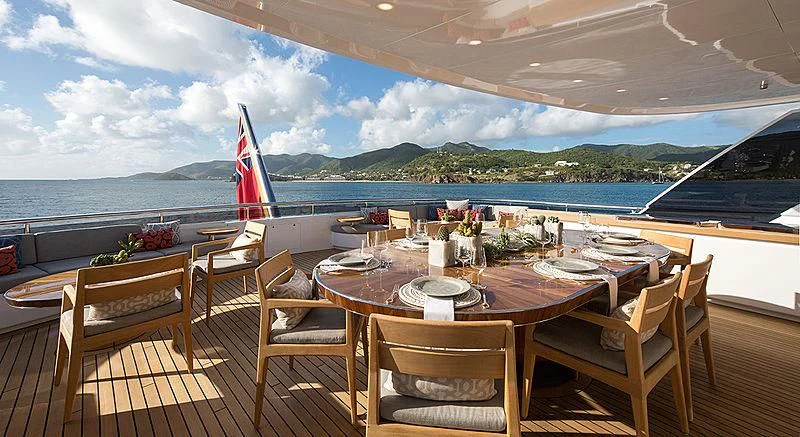 a table set for a meal on a deck overlooking a large body of water aboard REVERIE Yacht for Sale
