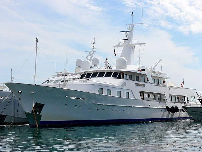 a large white boat in the water with USS Potomac (AG-25) in the background aboard KALINGA Yacht for Sale