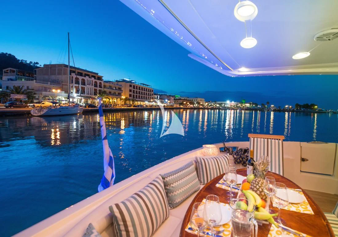 a table with food on it by a pool with boats and buildings in the background aboard MANU Yacht for Charter
