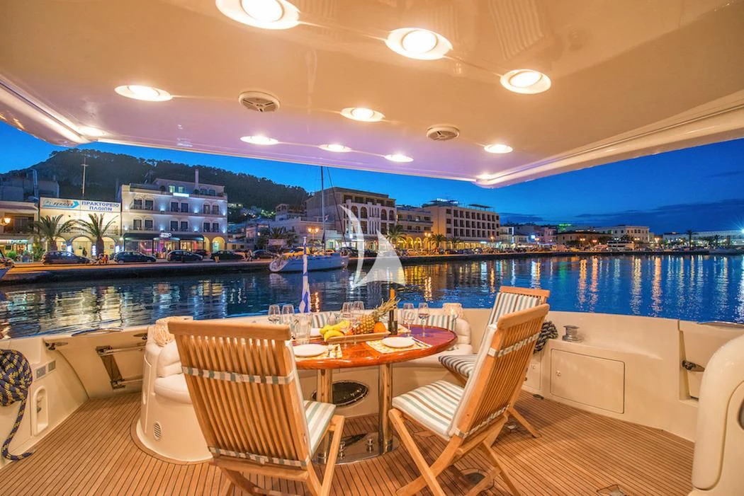 a room with a table chairs and a view of a city aboard MANU Yacht for Charter