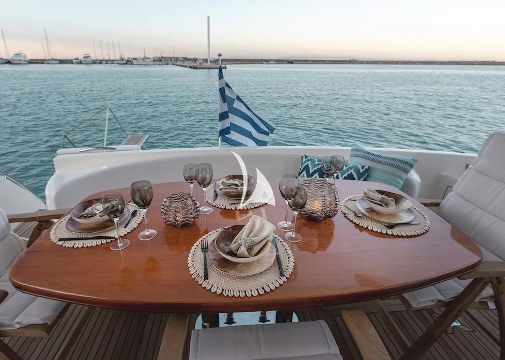 a table with food and glasses on it by a body of water aboard MANU Yacht for Charter