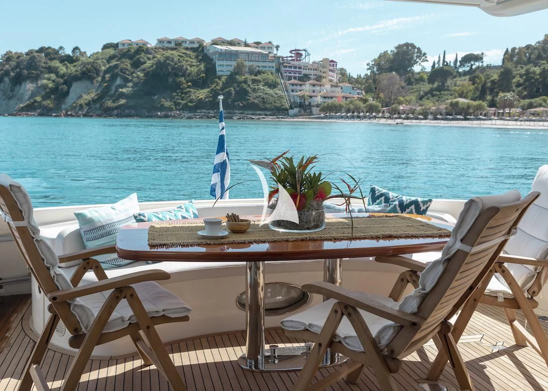 a table and chairs on a patio overlooking a body of water aboard MANU Yacht for Charter