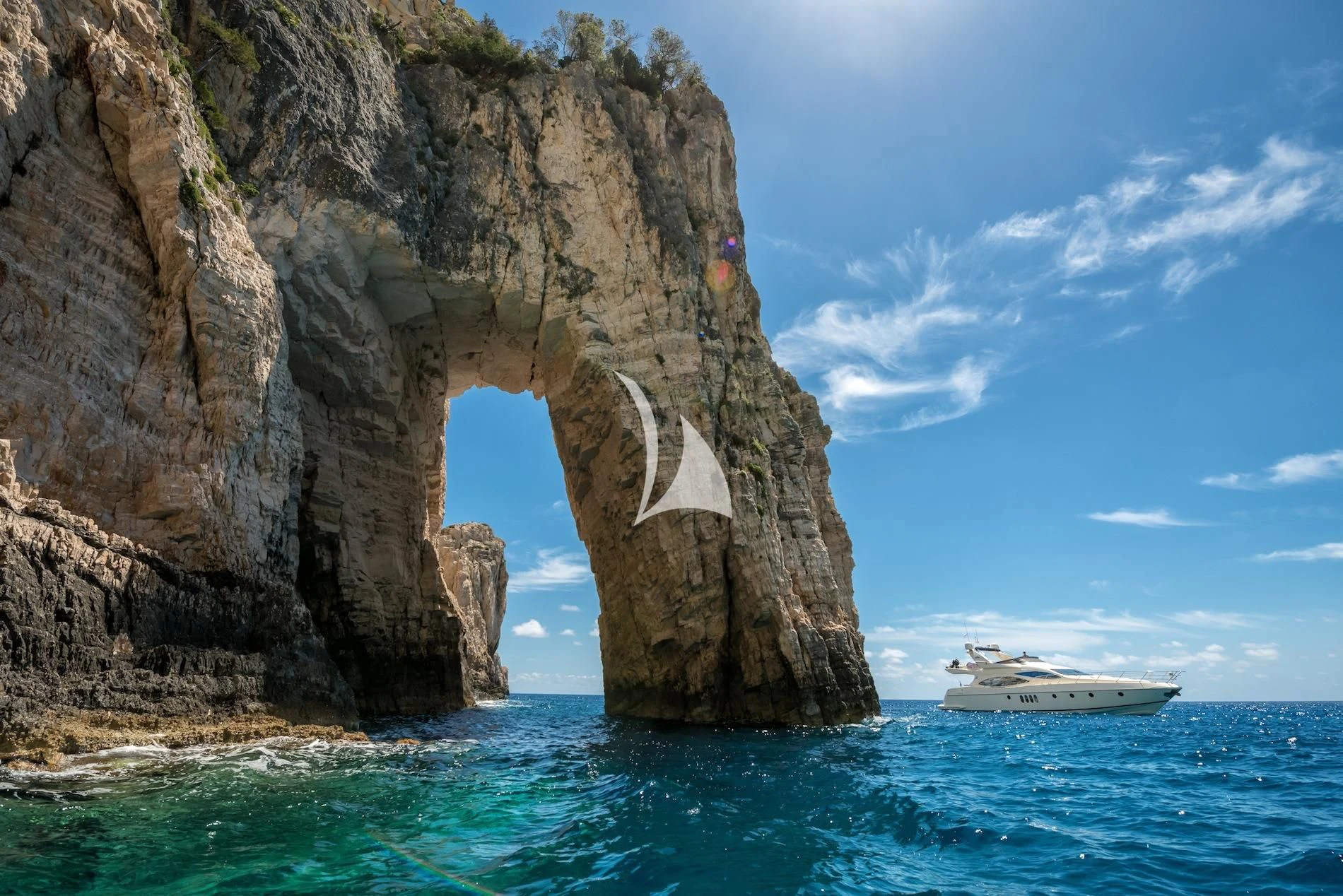 a boat in the water by a rock arch aboard MANU Yacht for Charter