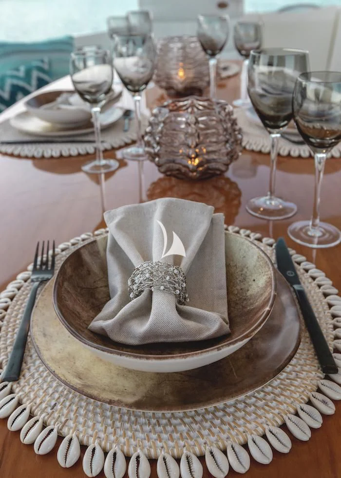 a table with a plate of food and glasses on it aboard MANU Yacht for Charter