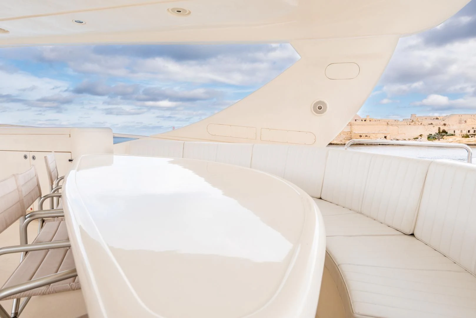 a white lounge chair on a balcony overlooking a beach and water aboard ALPINN Yacht for Sale