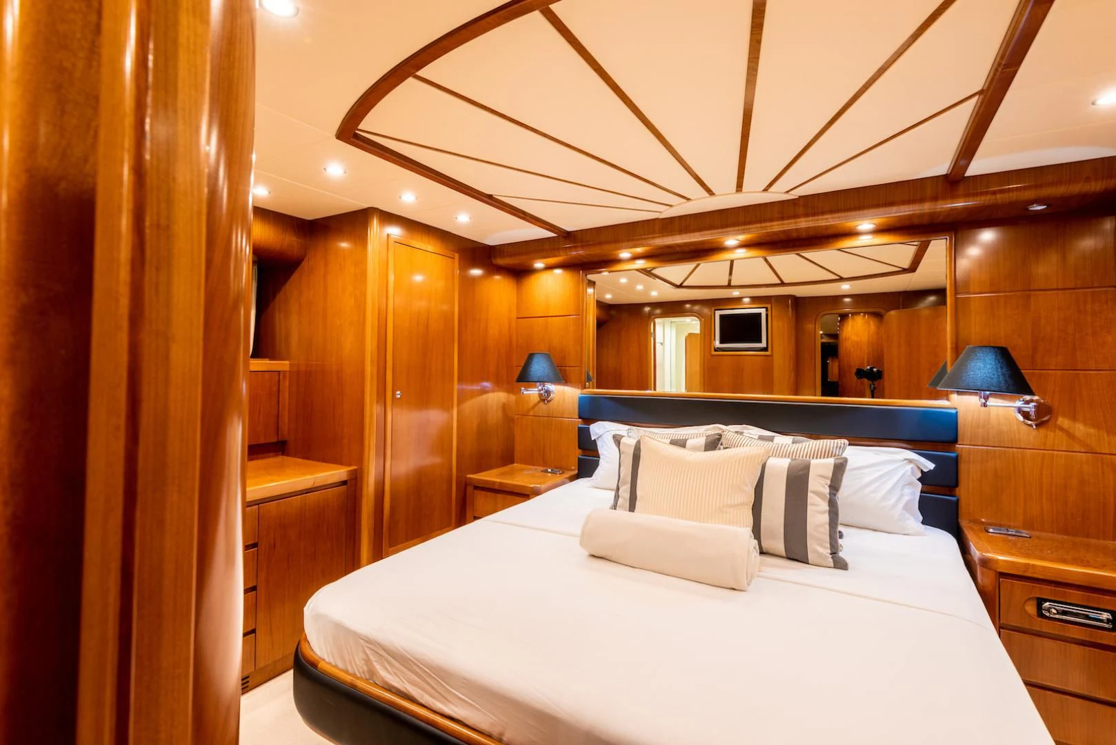 a bed with a white sheet and pillows in a room with wood walls aboard ALPINN Yacht for Sale