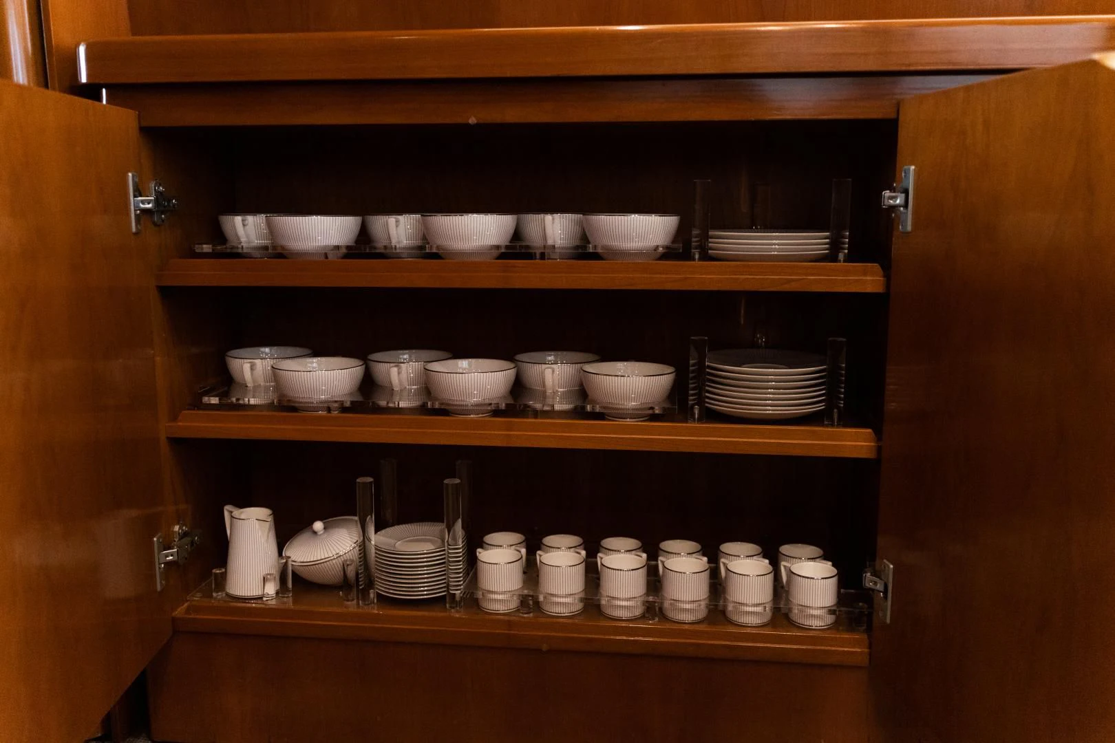 a wooden cabinet with many white dishes aboard ALPINN Yacht for Sale