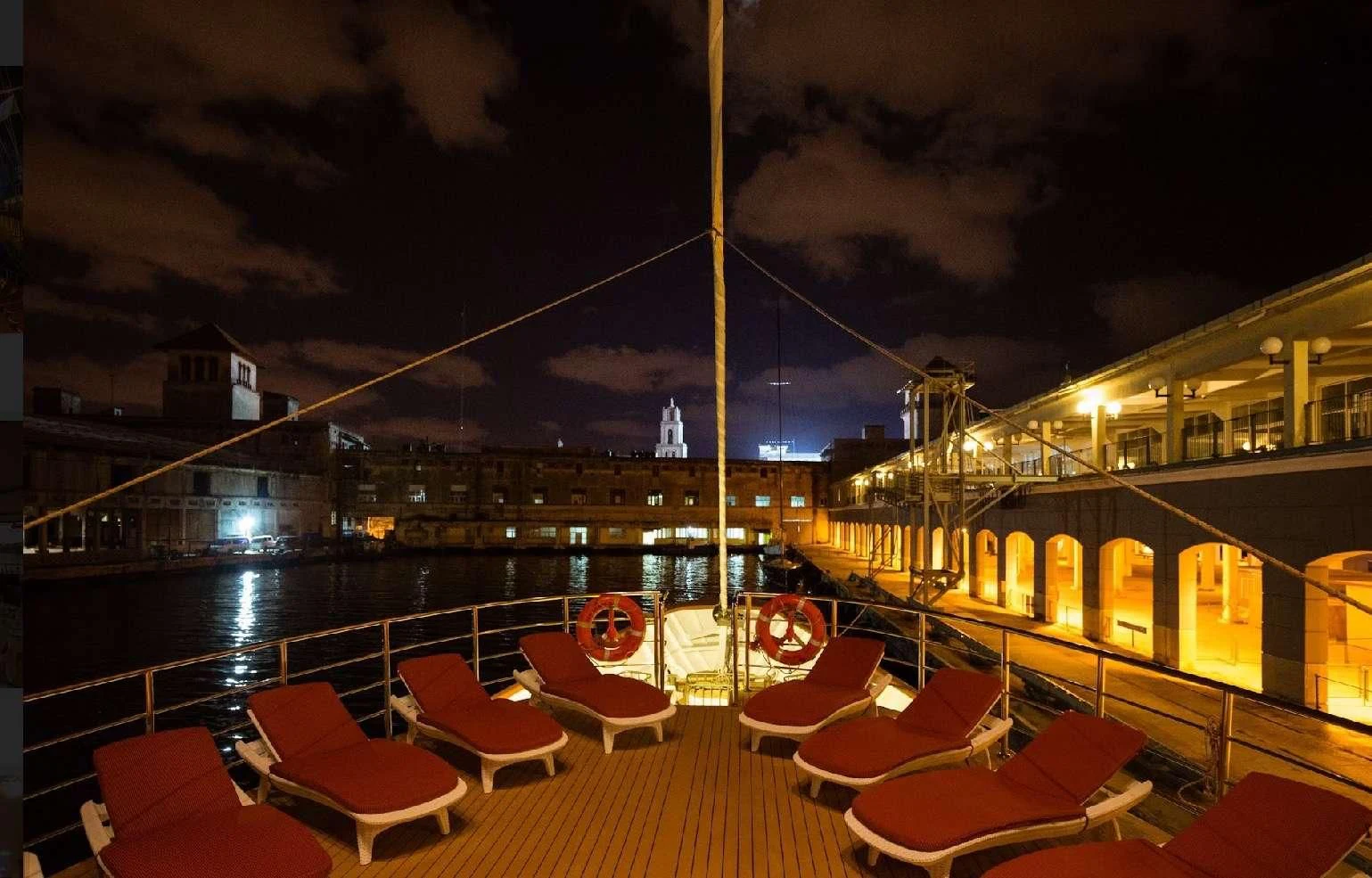 a deck with tables and chairs on it and a building in the background aboard PAN ORAMA II Yacht for Sale