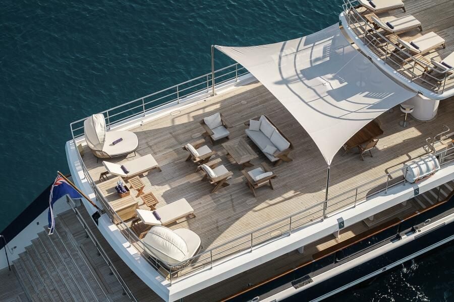 a large deck with chairs and tables on it next to a body of water aboard KORU Yacht for Charter
