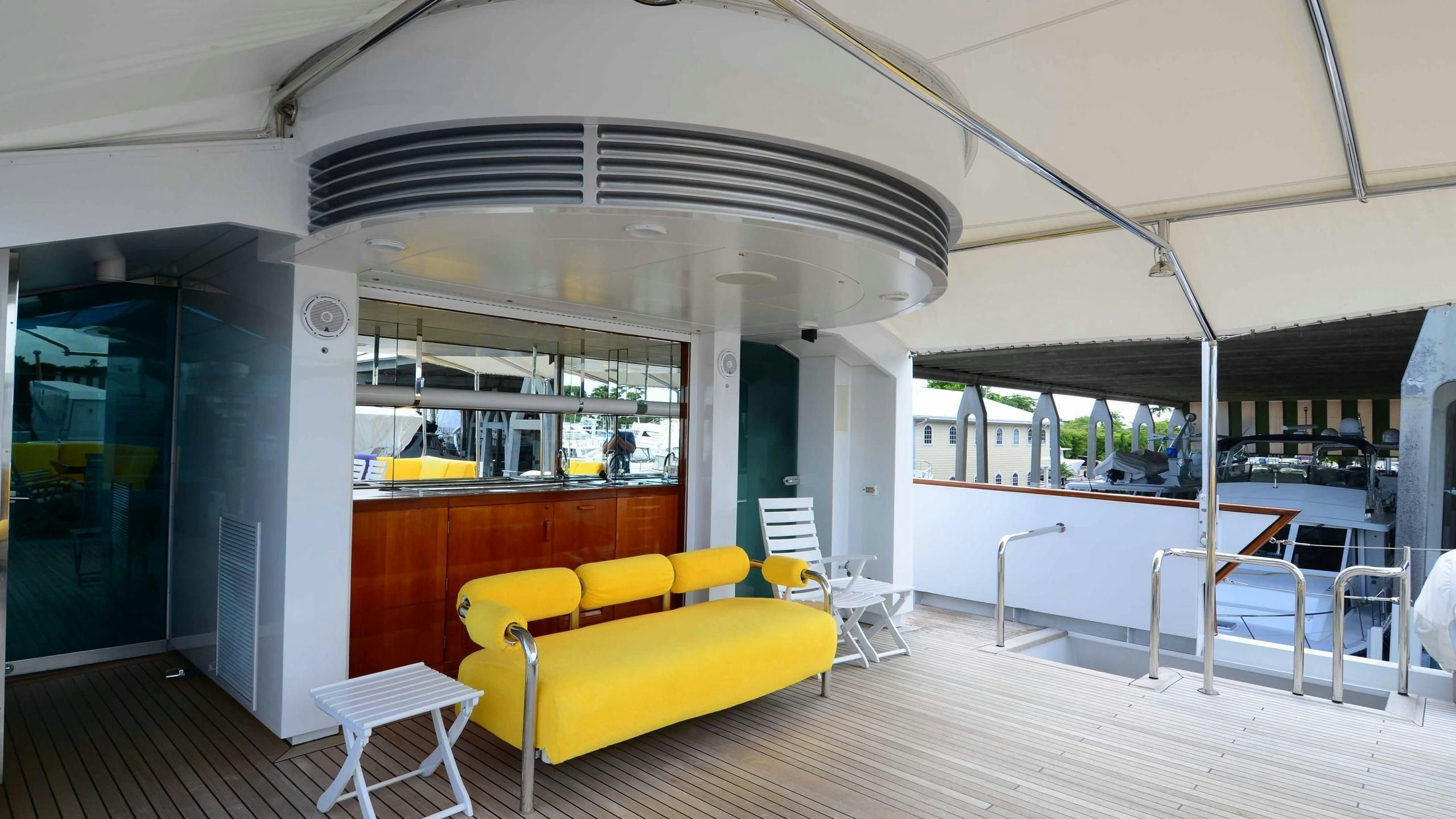 a room with a yellow couch and a white umbrella aboard KORU Yacht for Charter