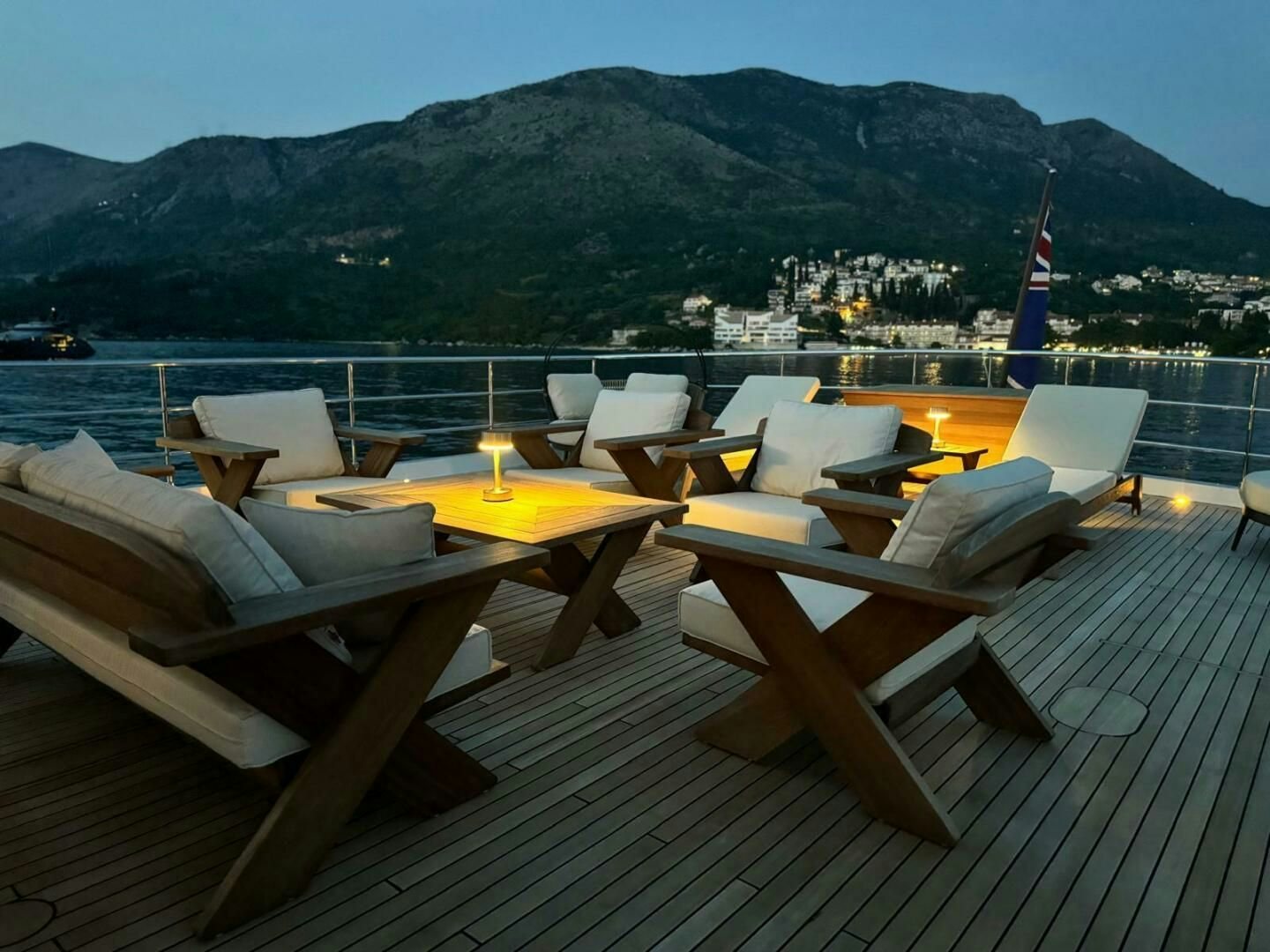 a deck with chairs and a view of a city and mountains in the background aboard KORU Yacht for Charter
