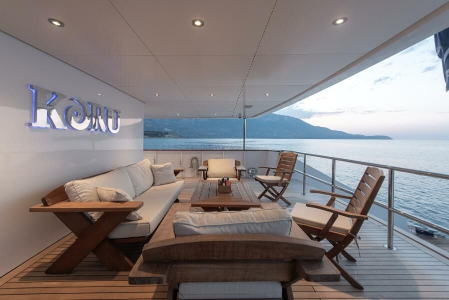 a room with a bed and a table and chairs on a boat aboard KORU Yacht for Charter
