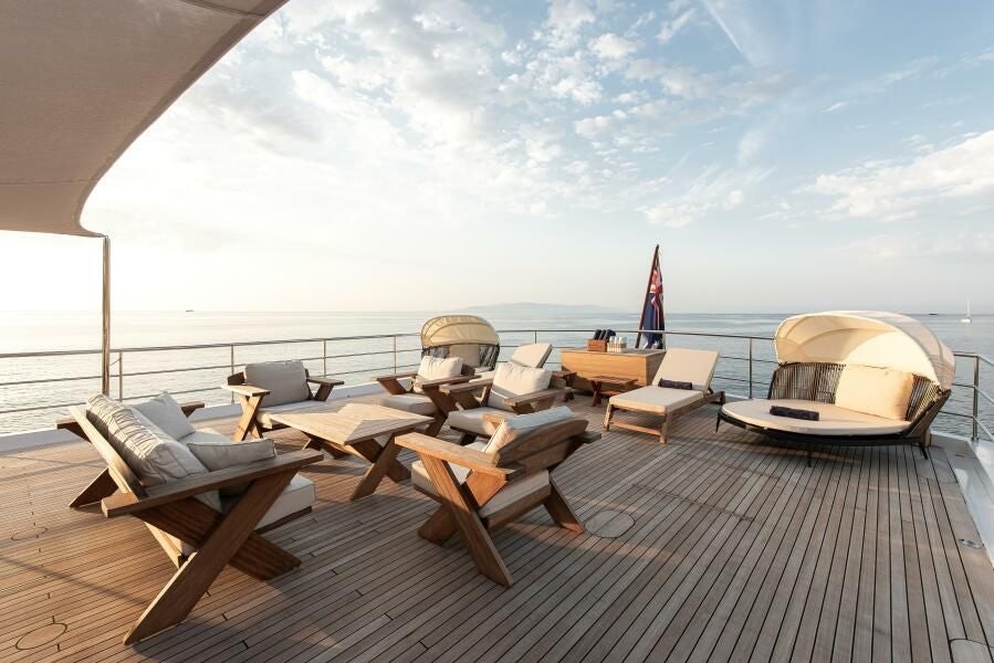a deck with chairs and a boat on it aboard KORU Yacht for Charter