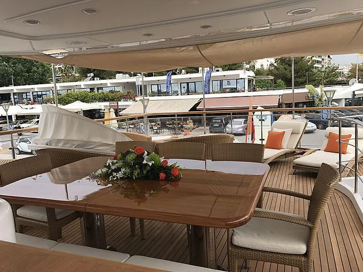 a table with chairs and a large umbrella on it aboard AKUA Yacht for Sale