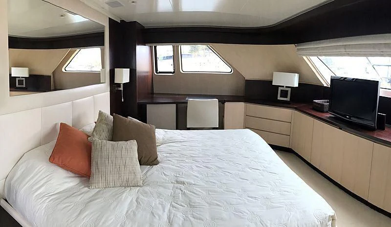 a bed with pillows and a television aboard AKUA Yacht for Sale