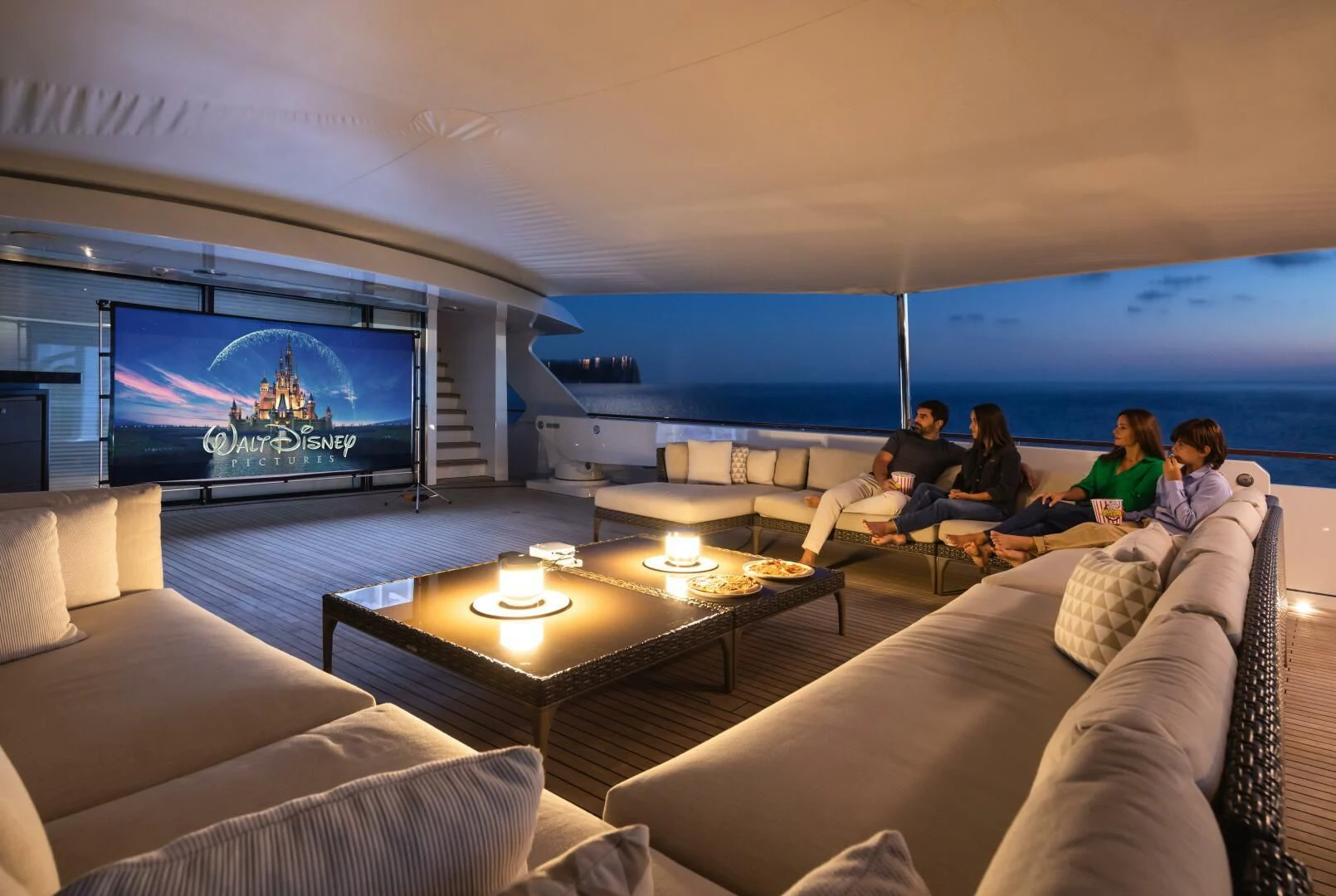 a group of people sitting on a couch watching a large screen aboard MIRAGE Yacht for Sale
