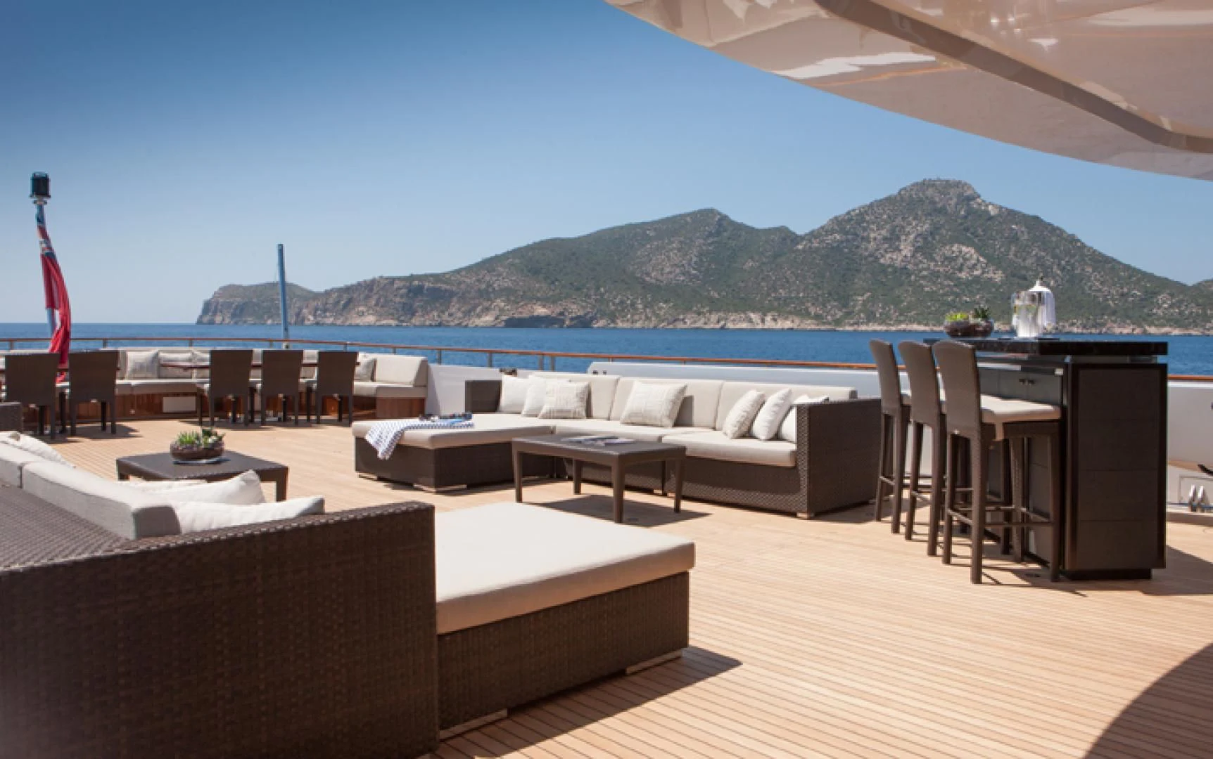 a room with a couch and a table and chairs with a body of water in the background aboard MIRAGE Yacht for Sale
