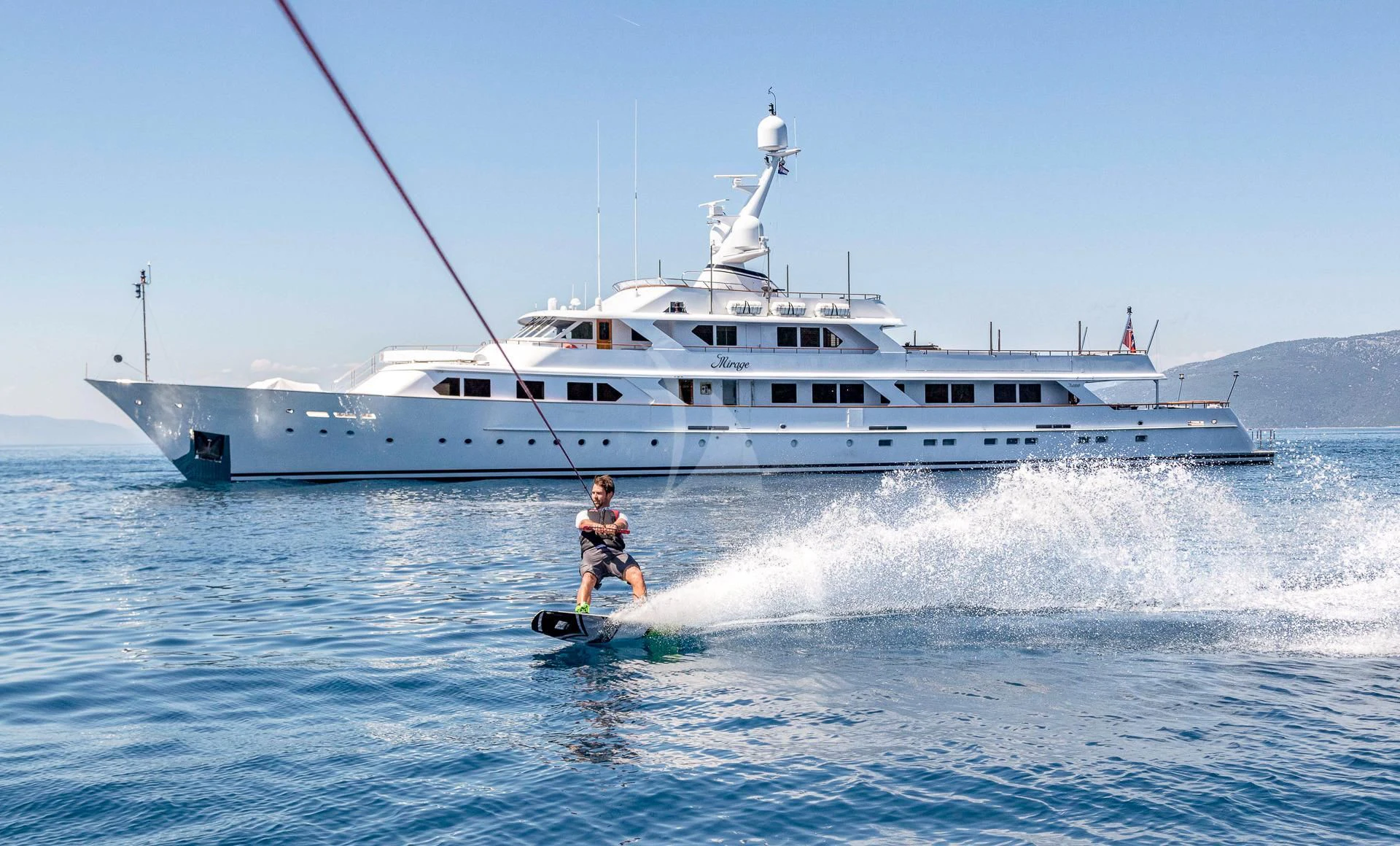a person on a surfboard in front of a boat aboard MIRAGE Yacht for Sale
