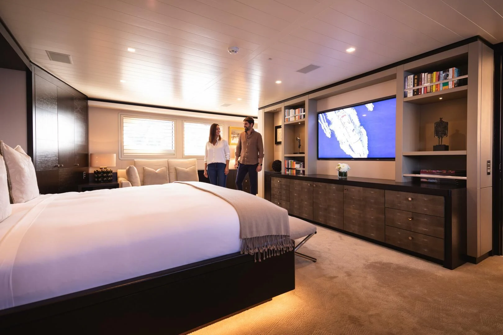 a couple of people standing in a room with a large bed aboard MIRAGE Yacht for Sale