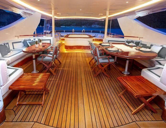 a room with a wood floor and a pool table with chairs and a large pool in the background aboard AQUA MARE Yacht for Sale