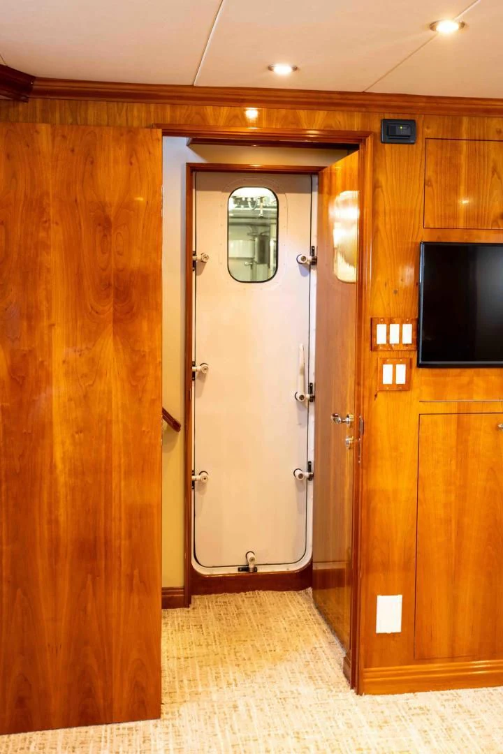 a room with a door and a tv on the wall aboard WELL DONE Yacht for Sale