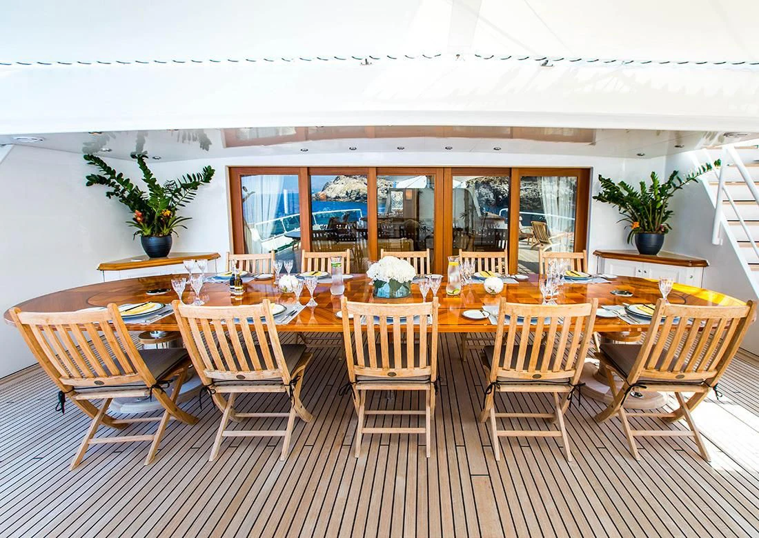 a table with chairs and flowers aboard ESMERALDA Yacht for Sale