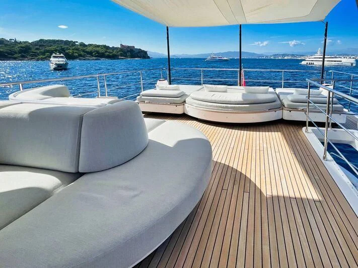 a deck with white pillows on it and a body of water in the background aboard WAVE Yacht for Sale
