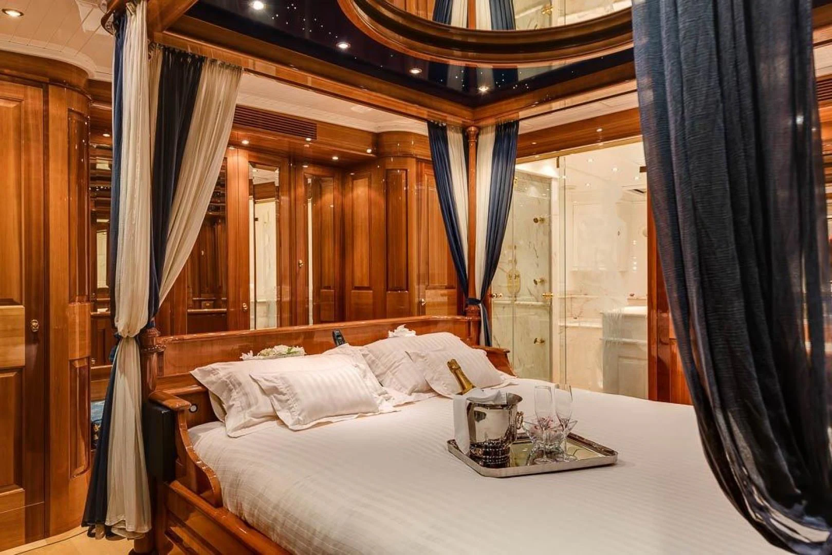 a bed with a white sheet and a black curtain aboard DELUSHA Yacht for Sale