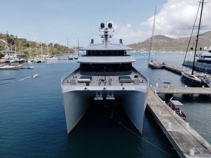 a large white boat sits at a dock aboard NEBULA Yacht for Sale
