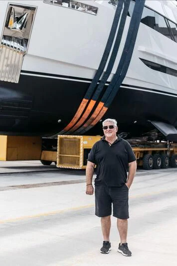 a man standing in front of a large boat aboard FAMILIA Yacht for Sale