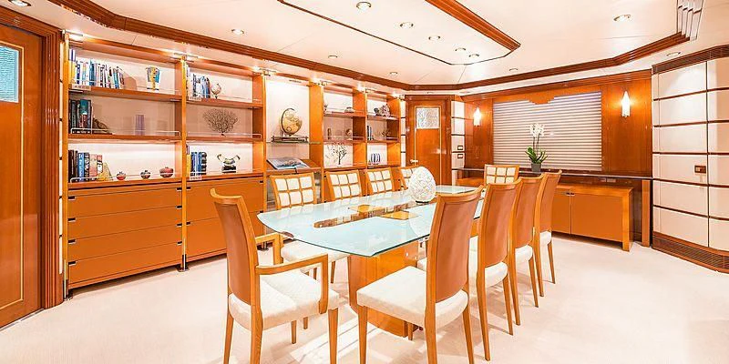 a room with a table chairs and a bookcase aboard B5 Yacht for Sale